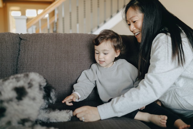 mother with a young baby & a dog teaching baby to touch the dog gently